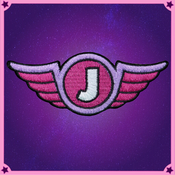 a stitched, four colour version of the Jimquisition logo, a white J on a pink circle, ringed by purple, with pink wings, outlined in black
